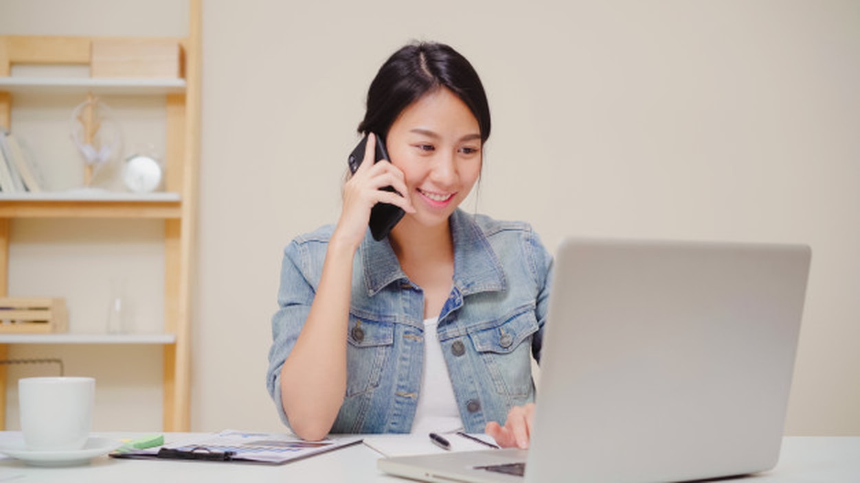 An Xcaliber direct booking assistant on the phone to a hotel, working at a laptop